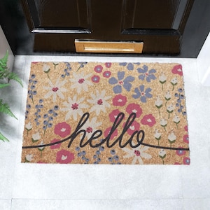 May include: A coir doormat with a floral pattern in shades of pink, white, and blue. The word "hello" is written in black cursive across the mat.