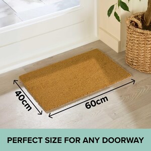 May include: A rectangular doormat, 60cm long and 40cm wide, made of a natural brown material. The mat is placed in front of a white door and has the text "PERFECT SIZE FOR ANY DOORWAY".