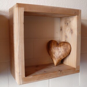 May include: A wooden shelf with a carved wooden heart on the shelf. The shelf is made of light wood and has a simple design.