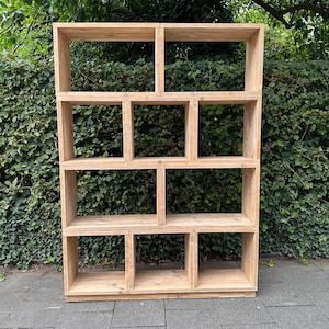 Könnte beinhalten: Ein Holzregal mit mehreren offenen Fächern. Das Regal ist aus Naturholz mit einer hellbraunen Oberfläche. Das Regal ist freistehend und hat ein schlichtes, modernes Design.