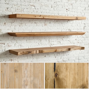 May include: Three horizontal wooden floating shelves mounted on a white brick wall. The shelves feature a natural light brown wood grain with visible knots and a raw, uneven live edge on the bottom shelf, showcasing wood texture.