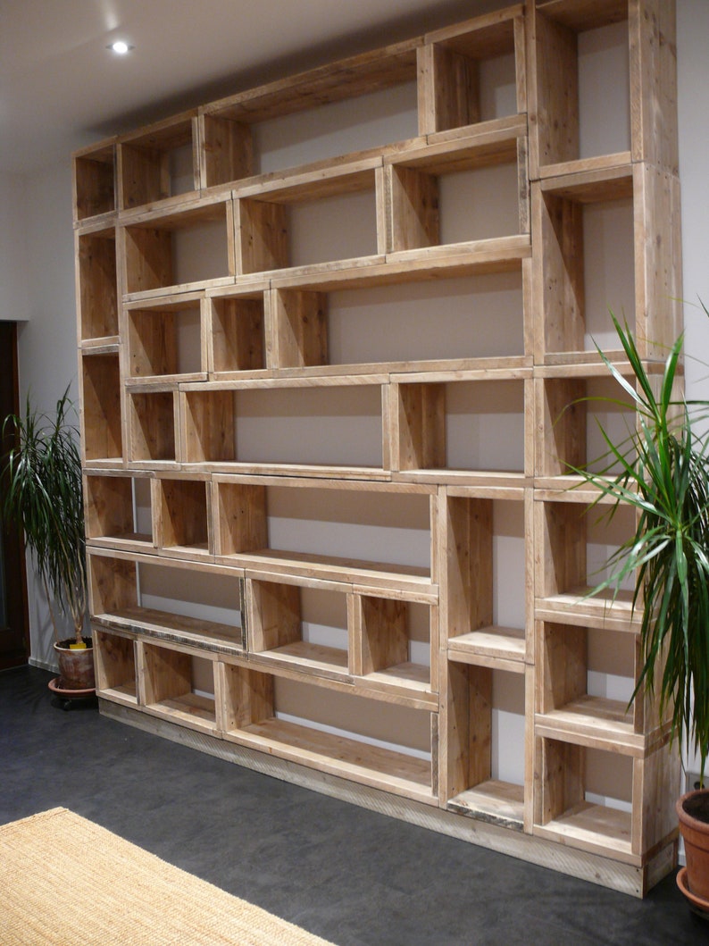 May include: A large, rustic wooden bookshelf with multiple shelves of varying sizes. The shelves are made of reclaimed wood and have a natural, unfinished look. The bookshelf is perfect for displaying books, plants, or other decorative items.