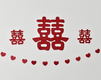 May include: Red paper cutouts of the Chinese character "double happiness" in various sizes, with a red heart garland strung below.