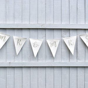May include: White fabric bunting with silver glitter lettering spelling "Mr & Mrs" with a heart on each end.