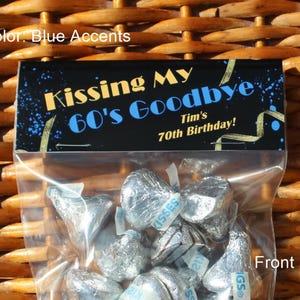 May include: A black and gold favour bag with a blue accent, featuring the text "Kissing My 60's Goodbye" and "Tim's 70th Birthday!" The bag is filled with silver foil-wrapped chocolate kisses.