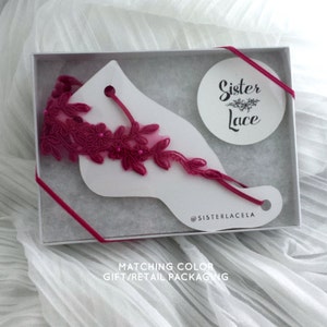May include: A pink lace garter in a white gift box with a pink ribbon. The box has a white circle sticker with the text "Sister Lace" and the text "@sisterlacela" printed on the bottom. The box also has the text "Matching Color Gift/Retail Packaging" printed on the bottom.