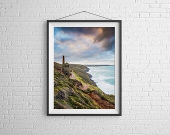 Könnte beinhalten: Ein gerahmtes Foto eines verwitterten, verlassenen Gebäudes mit einem hohen Schornstein auf einer Klippe mit Blick auf ein stürmisches Meer. Der Himmel ist eine Mischung aus Grau und Blau mit dramatischen Wolken.