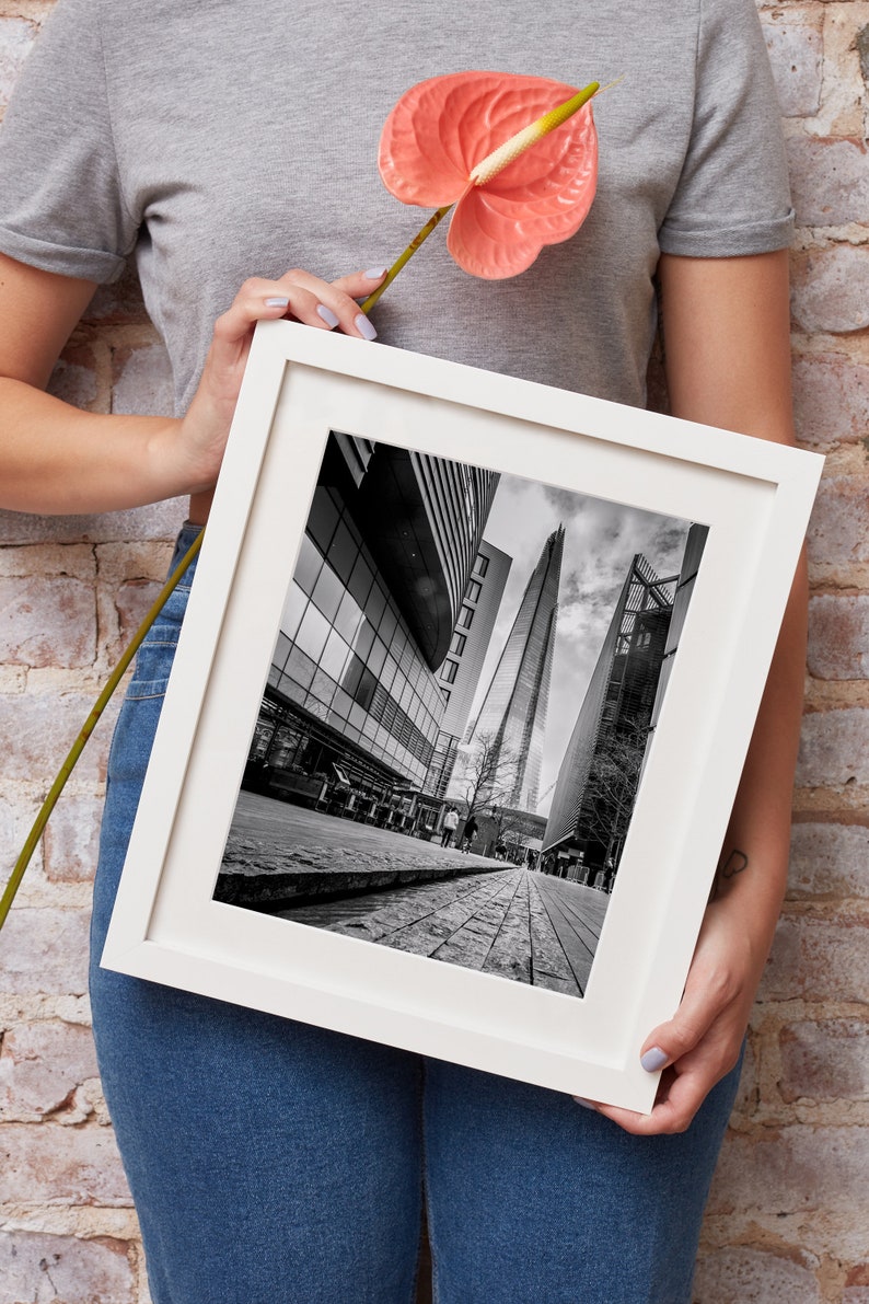 May include: A black and white photograph of the Shard, a skyscraper in London, England, framed in a white frame.