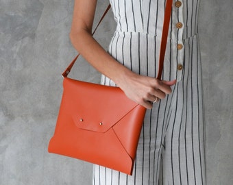 Burnt orange leather clutch bag with a removable shoulder strap