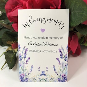 May include: A white card with purple text that reads "in loving memory". A small purple heart is below the text. The card also includes the text "Plant these seeds in memory of Maise Peterson 10/12/1939 - 07/14/2022". The card is decorated with a watercolor design of lavender flowers.