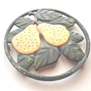 Peut inclure: Un dessous de plat en fonte avec un motif de deux poires et de feuilles. Les poires sont jaunes avec des taches brunes et les feuilles sont vertes.