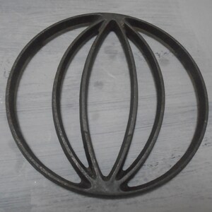 May include: A cast iron round baking mould with a decorative design of three overlapping circles. The mould is grey and has a smooth surface.