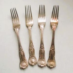 Op de afbeelding: Vier zilveren vorken met sierlijke ontwerpen op de handvatten.