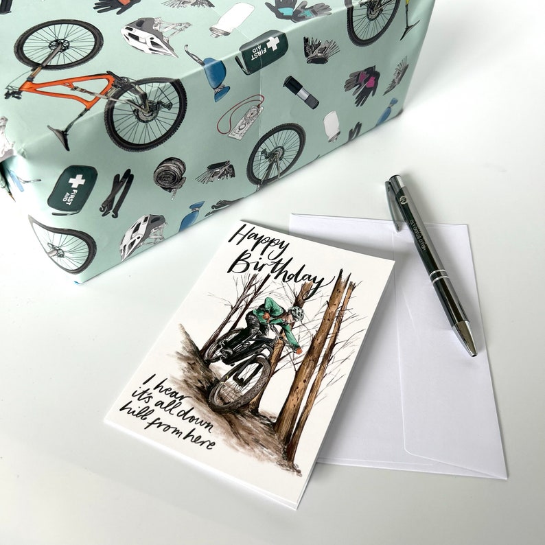 May include: A white card with a mountain biking illustration and the text "Happy Birthday! I hear it's all down hill from here".