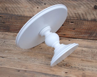 May include: White cake stand with a round top and a pedestal base. The stand is made of wood and has a smooth, painted finish.