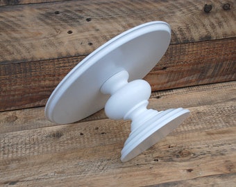 May include: White cake stand with a round top and a pedestal base. The stand is made of wood and has a smooth, painted finish.
