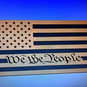 Puede incluir: Bandera americana de madera con las palabras "We the People" en una fuente cursiva.