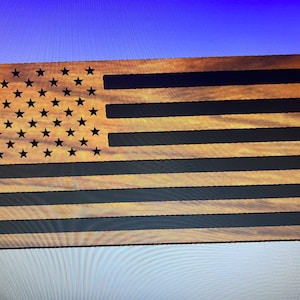 Puede incluir: Una bandera americana de madera con un acabado de madera desgastado. Las estrellas están cortadas en la madera y las rayas están pintadas de negro.