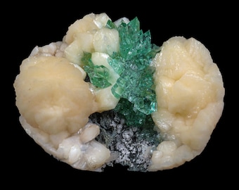 May include: A cluster of green and white crystals on a dark background. The green crystals are sharp and pointed, while the white crystals are rounded and smooth.