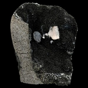 May include: A close-up of a dark grey rock with a small, light pink crystal and a smaller, dark grey crystal embedded in it.
