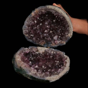 May include: Two halves of a large amethyst geode, revealing a cluster of purple crystals inside.