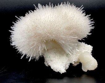 May include: A white crystal cluster with a large, spiky, white crystal formation on top. The crystal cluster is on a black background.