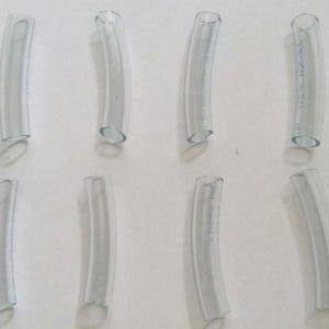 Pode incluir: Dez tubos de plástico transparente, cada um dobrado em uma ligeira curva. Os tubos medem aproximadamente 3,8 cm de comprimento e 1,3 cm de diâmetro.