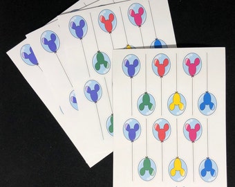 May include: A set of printable party favour tags featuring colourful balloons with Mickey Mouse ears. The tags are printed on white cardstock and have a whimsical design. The text "dogbones.academy" is printed at the bottom of the tags.