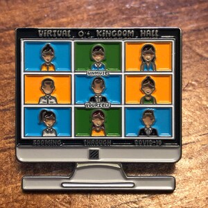 Op de afbeelding: Een zilverkleurige computermonitor pin met een zwarte rand. Het scherm toont een videogesprek met negen deelnemers in kleurrijke vakken. Tekst bevat "Virtual O. Kingdom Hall", "Unmute Yourself", "Zooming Through Covid-19".