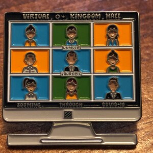 Op de afbeelding: Een zilverkleurige pin in de vorm van een computermonitor. Het scherm toont negen kleine vakjes met cartoonfiguren, elk in een andere kleur. De tekst op de pin luidt "VIRTUAL O' KINGDOM HALL", "UNMUTE YOURSELF", "ZOOMING THROUGH COVID-19".