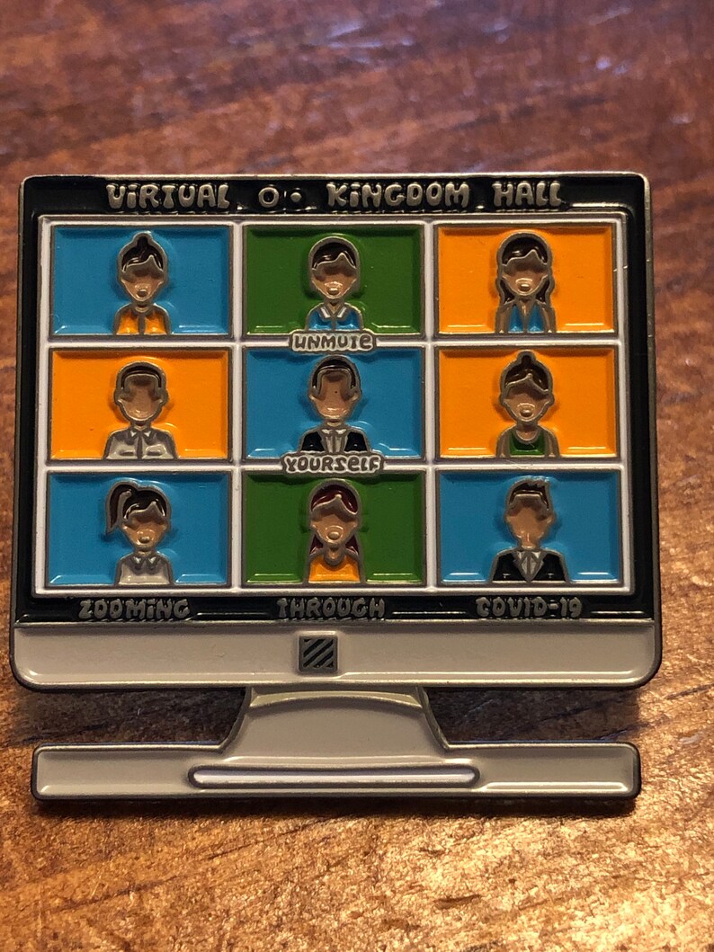 Op de afbeelding: Een zilverkleurige pin in de vorm van een computermonitor. Het scherm toont negen kleine vakjes met cartoonfiguren, elk in een andere kleur. De tekst op de pin luidt "VIRTUAL O' KINGDOM HALL", "UNMUTE YOURSELF", "ZOOMING THROUGH COVID-19".