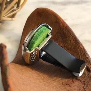 May include: Silver car air freshener with a black clip and a green scented pad.