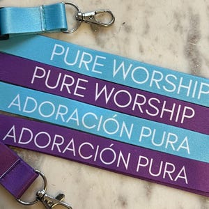 Cordón JW 2025 Adoración Pura [Inglés] / Adoración Pura [Español], disponible en color turquesa o morado, incluye porta credencial
