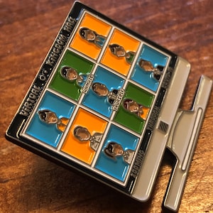Op de afbeelding: Een rechthoekige emaille pin met een computermonitor ontwerp. De pin heeft een raster van kleurrijke vierkanten met cartoonfiguren en de tekst "UNMUTE YOURSELF" en "ZOOMING THROUGH". De pin heeft een zilverkleurige rand.