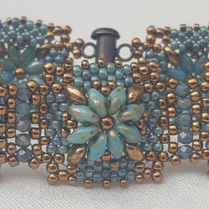 May include: A beaded bracelet with a turquoise and copper color scheme. The bracelet features a repeating pattern of small turquoise flowers surrounded by copper beads.