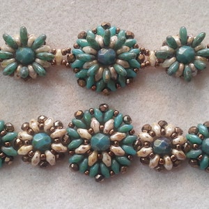 May include: Two rows of turquoise and white beaded bracelets with a flower design. The beads are arranged in a circular pattern, creating a floral motif.