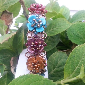 May include: A multi-coloured beaded bracelet with flower-shaped charms. The bracelet features turquoise, purple and orange beads.