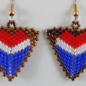 May include: A pair of triangle-shaped earrings with a red heart design in the center. The heart is surrounded by white and blue beads, creating a patriotic color scheme. The earrings are made with small, colorful beads and have gold-colored hooks.