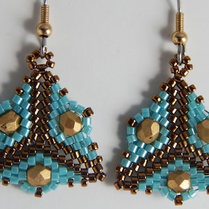 Puede incluir: Un par de pendientes colgantes con un diseño triangular. Los pendientes están hechos con cuentas marrones y turquesas y detalles dorados.
