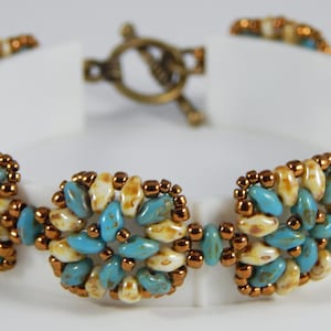 Può includere: Un braccialetto di perline turchesi e crema con una chiusura in bronzo. Il braccialetto è realizzato con piccole perline di forma irregolare.