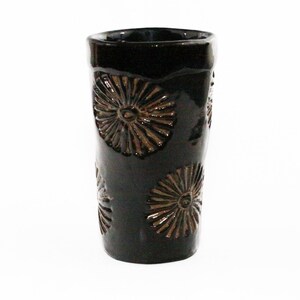 May include: A dark brown ceramic vase with a textured design of raised brown flowers.