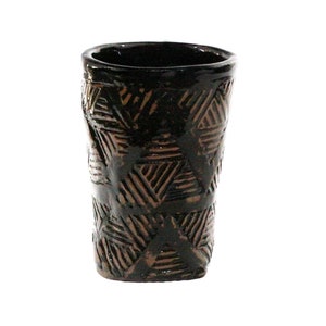 Peut inclure: Une tasse en céramique brune avec un motif géométrique. La tasse est recouverte d'un glaçage brun foncé et d'un motif brun clair de triangles et de lignes.