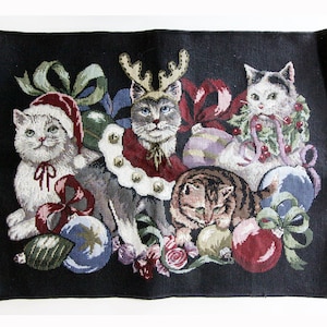 May include: A black tapestry with a Christmas theme featuring four cats. One cat is wearing a Santa hat, another is wearing a reindeer antler headband, and another is holding a sprig of holly. The cats are surrounded by Christmas ornaments and greenery.