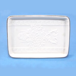 Saboneteira retangular de cerâmica branca com borda prateada, 10,8 cm de comprimento, com relevo e elegante.