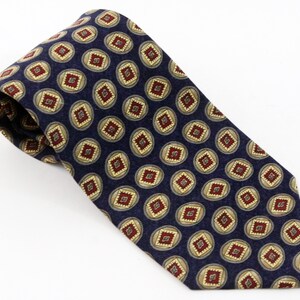 Puede incluir: Una corbata de seda azul marino con un patrón repetido de círculos dorados y rojos que contienen una forma de diamante.