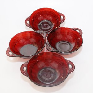 May include: Set of four red glass bowls with handles. The bowls have a ribbed design and are perfect for serving soup, salad, or dessert.
