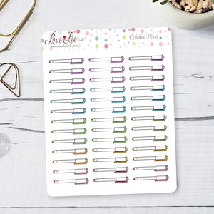 May include: A sheet of colorful pen stickers with a white background. The stickers feature a variety of colored pens with hearts on the ends. The text "Love Lee Ink" and "www.loveleeink.com" is at the top of the sheet. The text "Colored Pens" is at the top right of the sheet.