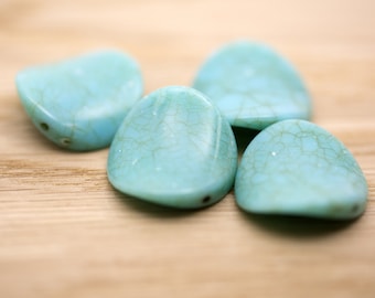May include: Four turquoise blue, irregularly shaped, smooth stones with a hole drilled through each. The stones have a marbled pattern.