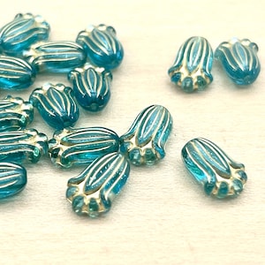 May include: A collection of blue glass beads with gold accents. The beads are shaped like a flower bud and have a textured surface.