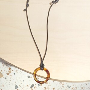 May include: A brown cord necklace with a tortoiseshell ring pendant.